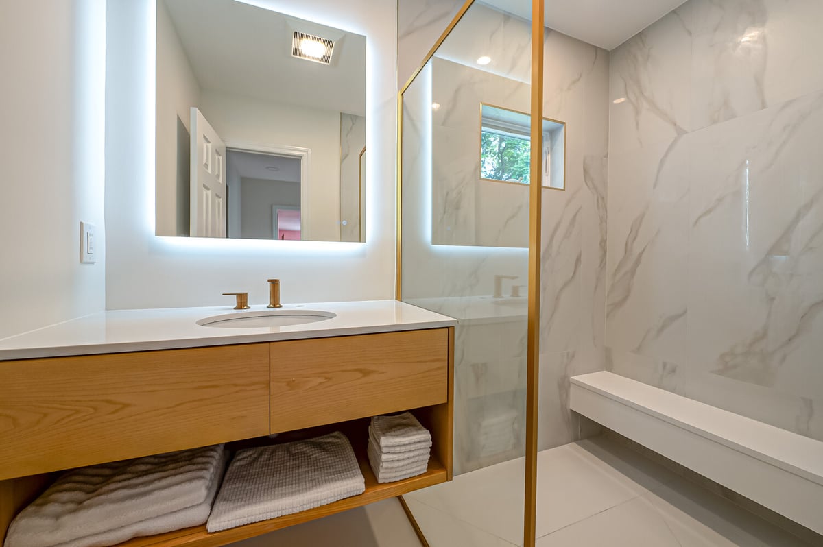 Modern bathroom vanity and illuminated mirror in a custom-built home by Long Island Creative Contracting in Stony Brook, NY