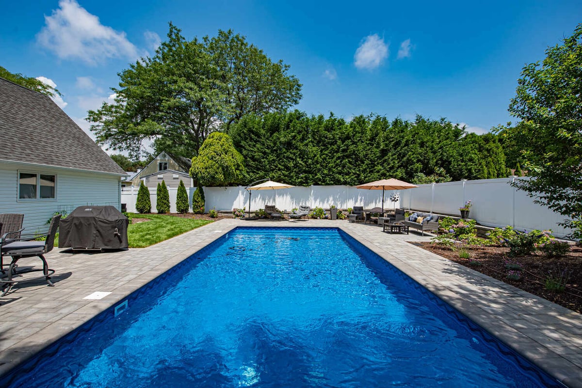 Crystal-clear custom pool with lush landscaping and paver patio by Long Island Creative Contracting in Miller Place, NY
