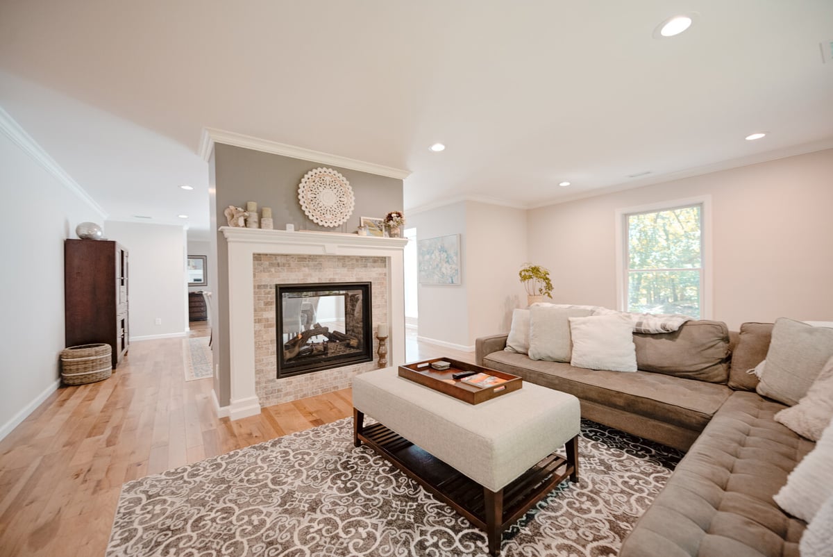 Stylish living room with L-shaped sectional and fireplace in a Port Jefferson custom home by Long Island Creative Contracting, Inc